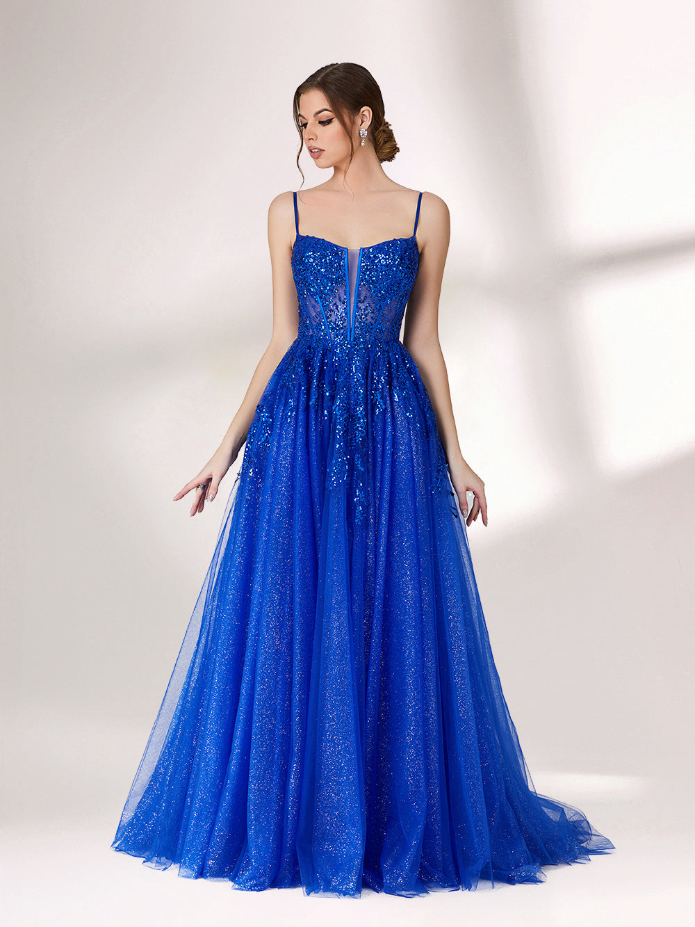 A woman stands against a light background, wearing a bright blue evening gown. It features thin spaghetti straps, a sweetheart neckline with a sheer, sequin - embellished bodice, and a voluminous tulle skirt that shimmers. The elegant design is perfect for formal events.3