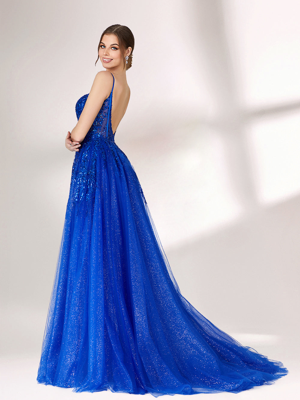 A woman stands against a light background, wearing a bright blue evening gown. It features thin spaghetti straps, a sweetheart neckline with a sheer, sequin - embellished bodice, and a voluminous tulle skirt that shimmers. The elegant design is perfect for formal events.2