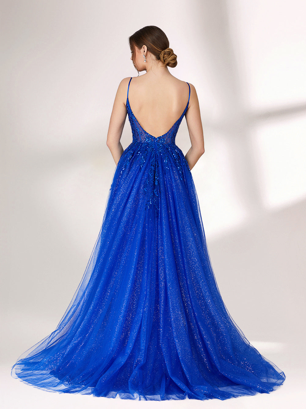 A woman stands against a light background, wearing a bright blue evening gown. It features thin spaghetti straps, a sweetheart neckline with a sheer, sequin - embellished bodice, and a voluminous tulle skirt that shimmers. The elegant design is perfect for formal events.4