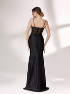 A woman poses against a light background, wearing a black evening gown. It has thin spaghetti straps, a corset - style bodice with sheer mesh detailing, and a high - slit satin skirt. The design is sexy and elegant, perfect for formal events.4