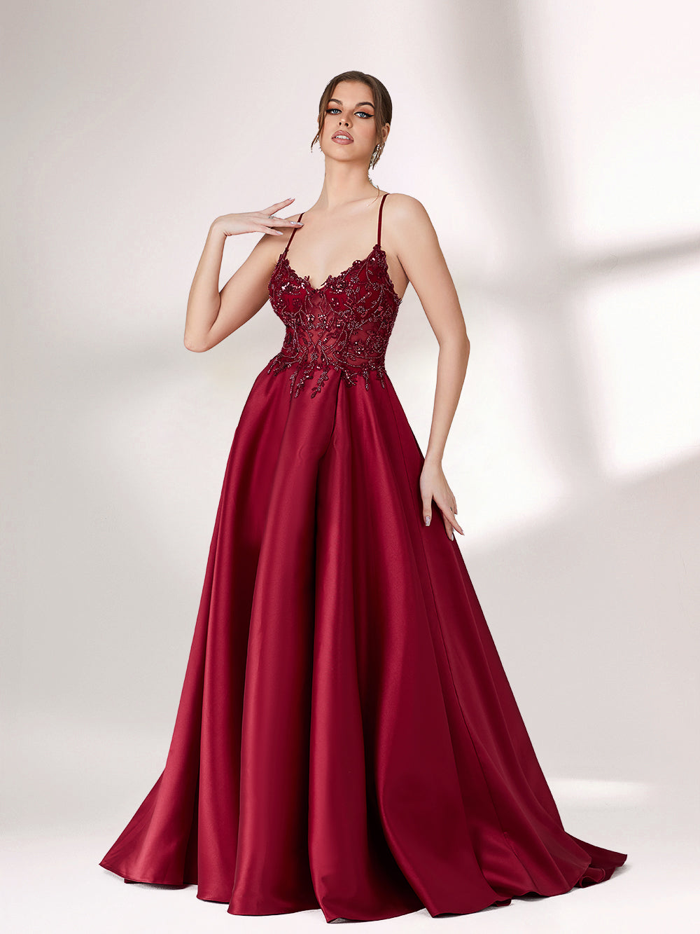 Bathed in soft light, a woman radiates elegance in a burgundy evening gown. With satin fabric, spaghetti straps, and lace embroidery, it crafts a luxurious and refined look for formal events.4