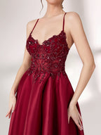 Bathed in soft light, a woman radiates elegance in a burgundy evening gown. With satin fabric, spaghetti straps, and lace embroidery, it crafts a luxurious and refined look for formal events.5