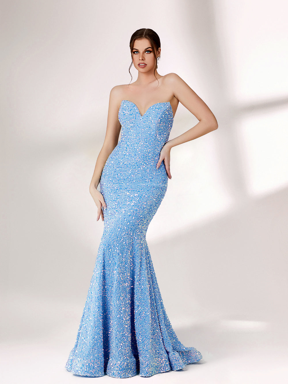 A woman stands against a light - colored backdrop, donning a stunning light blue mermaid - style evening gown. The strapless design features a sweetheart neckline, perfectly highlighting her shoulders and collarbone. The entire gown is intricately adorned with shimmering sequins, creating a dazzling effect that catches the light with every movement. This glamorous and elegant piece is an ideal choice for formal galas and upscale evening affairs.1