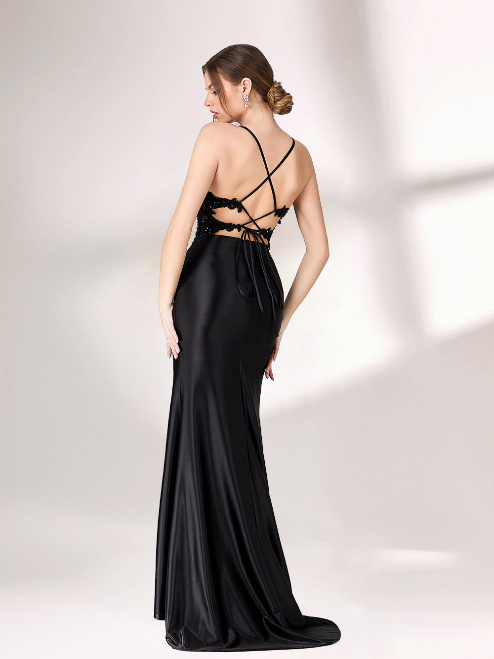 A woman stands against a light background, wearing a black evening gown. It features thin spaghetti straps, a deep V - neckline, intricate black bead and sequin embroidery on a sheer mesh upper, and a sleek satin skirt with a high side slit. The elegant design creates a glamorous and alluring look, perfect for formal events like galas or evening parties.2