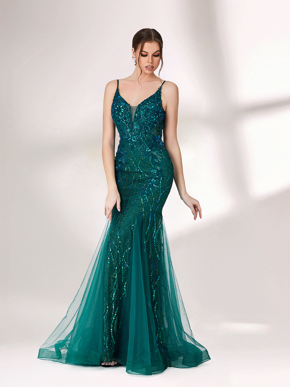 In soft lighting, a woman shines in a dark green evening gown. With sequin details, a mermaid silhouette, and tulle skirt, it creates a glamorous and elegant look for formal events.3