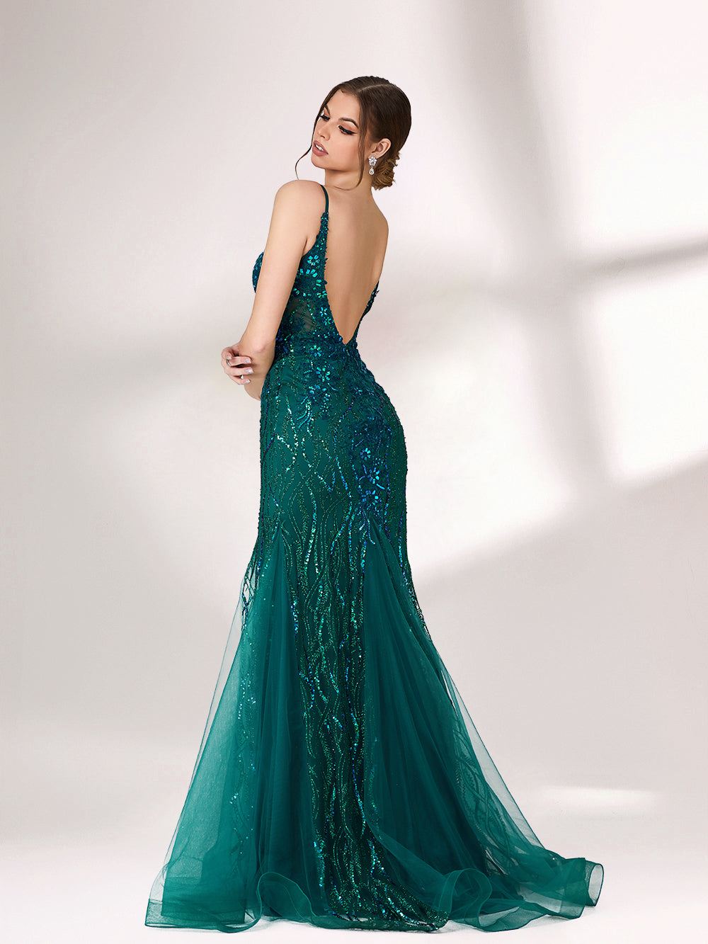 In soft lighting, a woman shines in a dark green evening gown. With sequin details, a mermaid silhouette, and tulle skirt, it creates a glamorous and elegant look for formal events.2