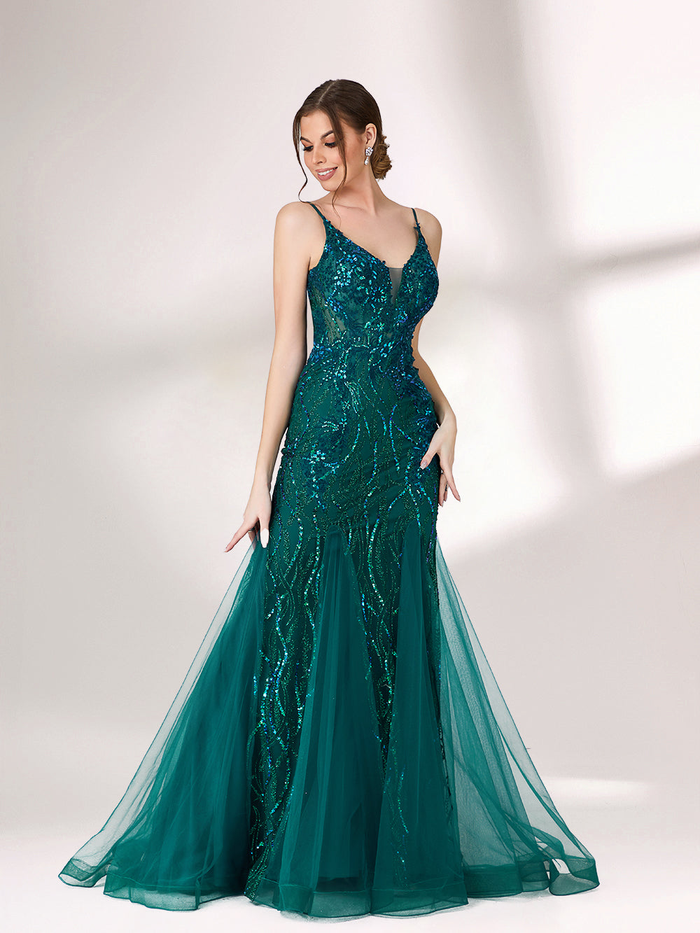 In soft lighting, a woman shines in a dark green evening gown. With sequin details, a mermaid silhouette, and tulle skirt, it creates a glamorous and elegant look for formal events.4