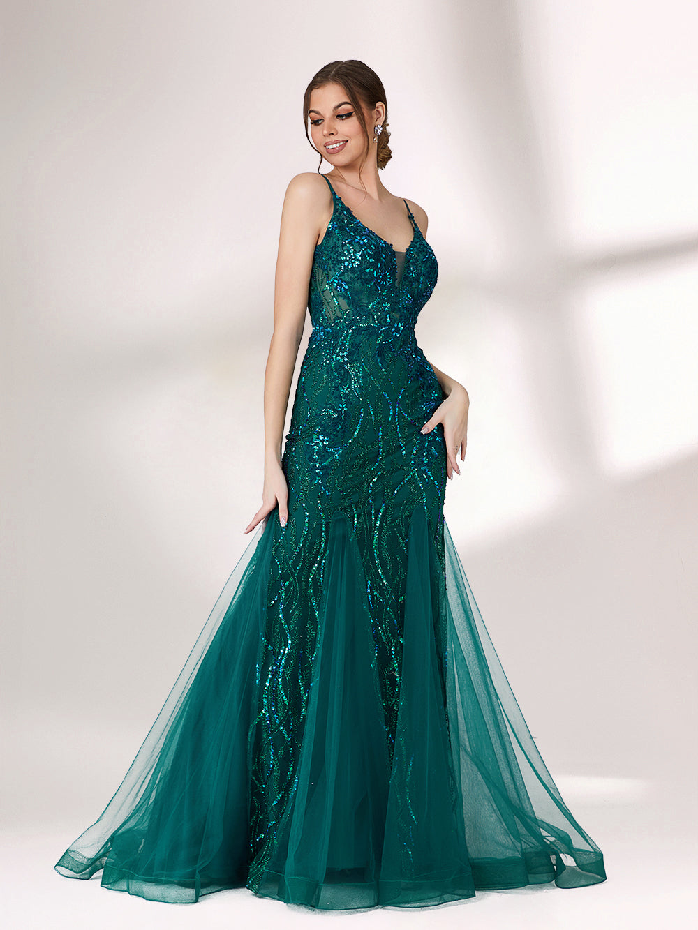 In soft lighting, a woman shines in a dark green evening gown. With sequin details, a mermaid silhouette, and tulle skirt, it creates a glamorous and elegant look for formal events.5