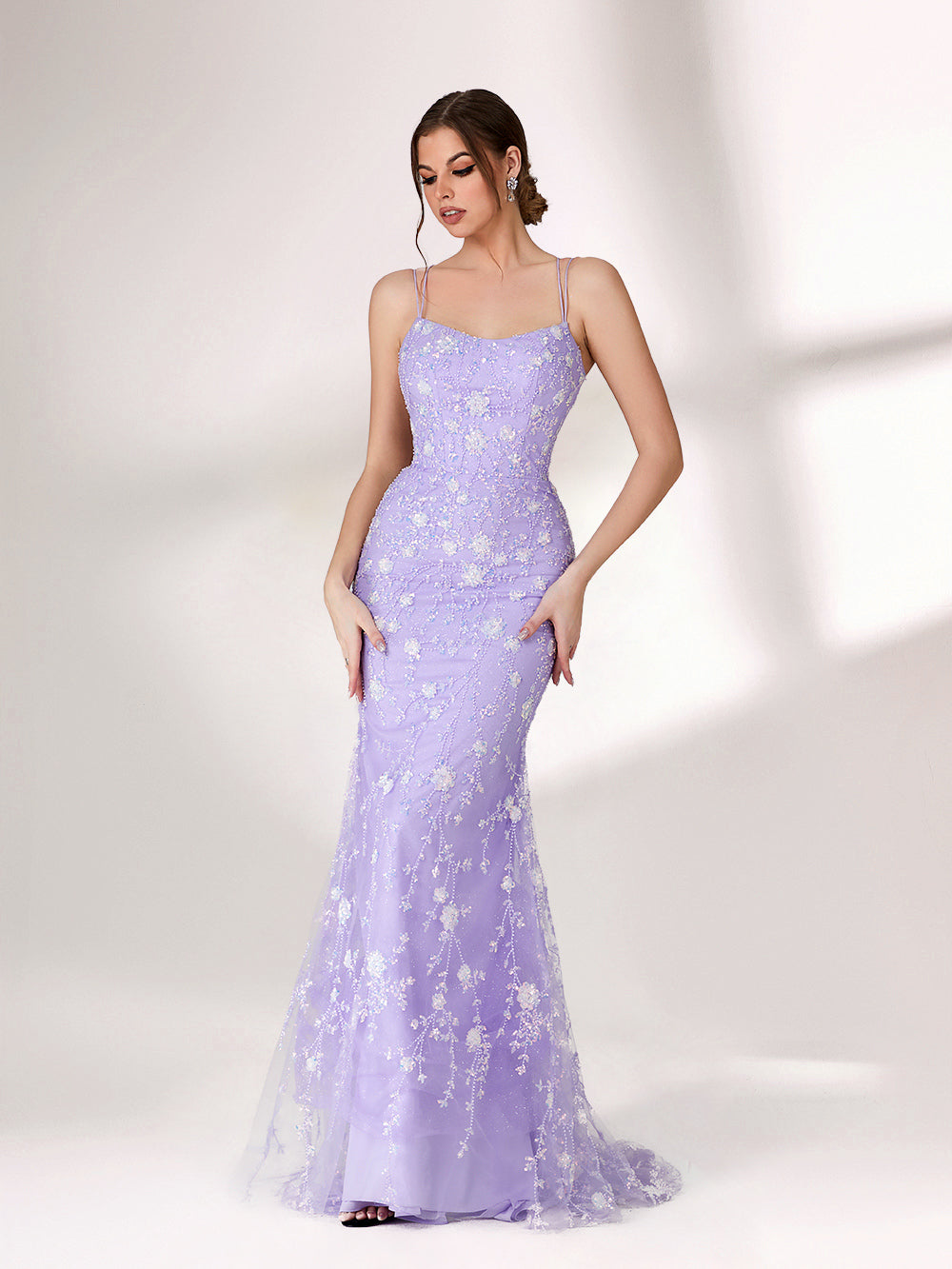 A woman stands against a light background, wearing a lavender mermaid - style evening gown. It has thin spaghetti straps, a sweetheart neckline, and is adorned with delicate white floral embroidery and beadwork throughout. The elegant design is perfect for formal events.1