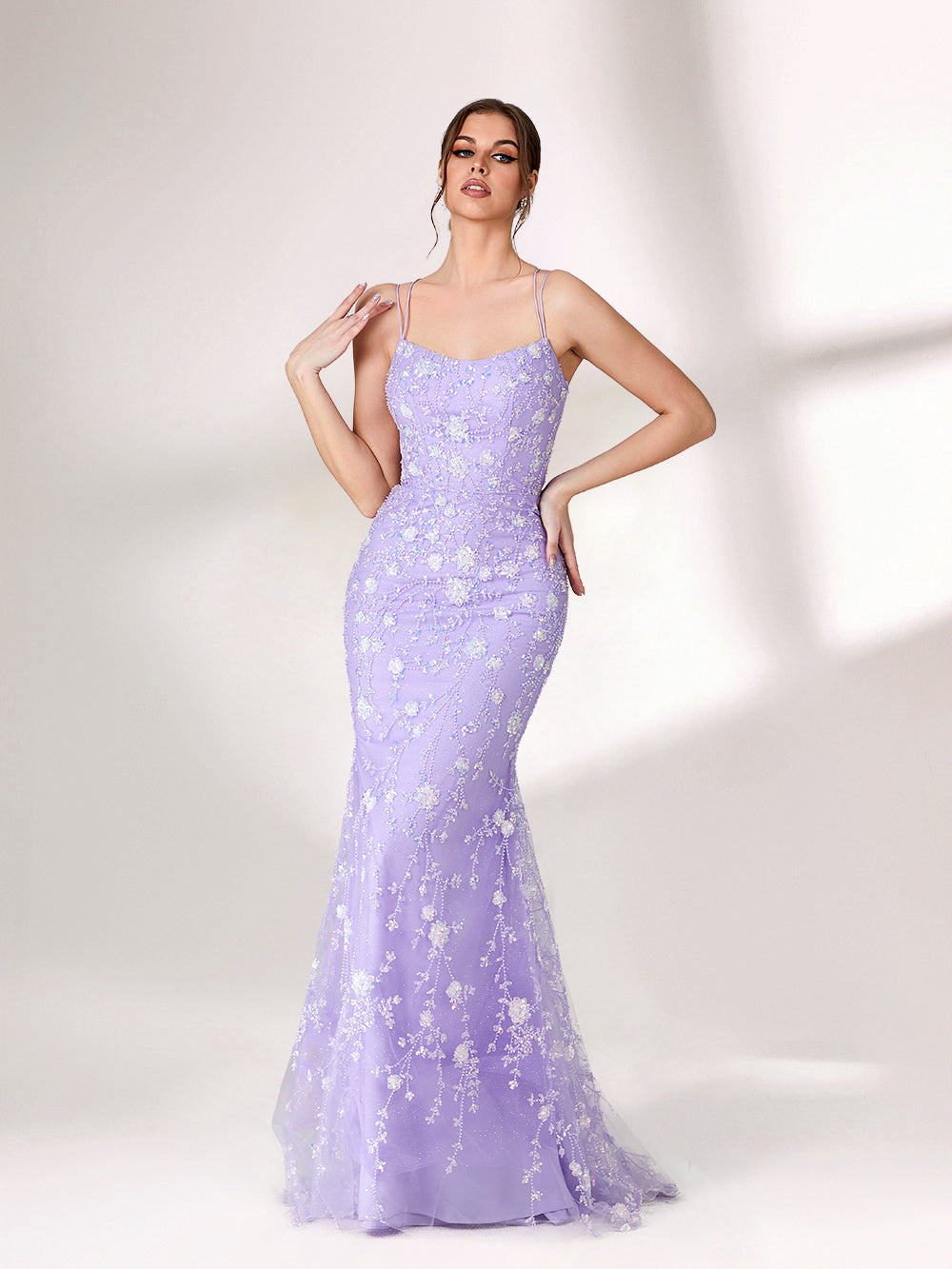 A woman stands against a light background, wearing a lavender mermaid - style evening gown. It has thin spaghetti straps, a sweetheart neckline, and is adorned with delicate white floral embroidery and beadwork throughout. The elegant design is perfect for formal events.3