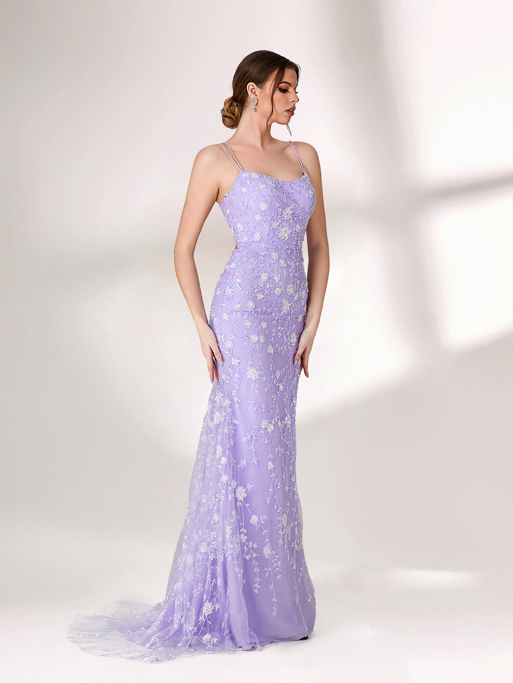 A woman stands against a light background, wearing a lavender mermaid - style evening gown. It has thin spaghetti straps, a sweetheart neckline, and is adorned with delicate white floral embroidery and beadwork throughout. The elegant design is perfect for formal events.5