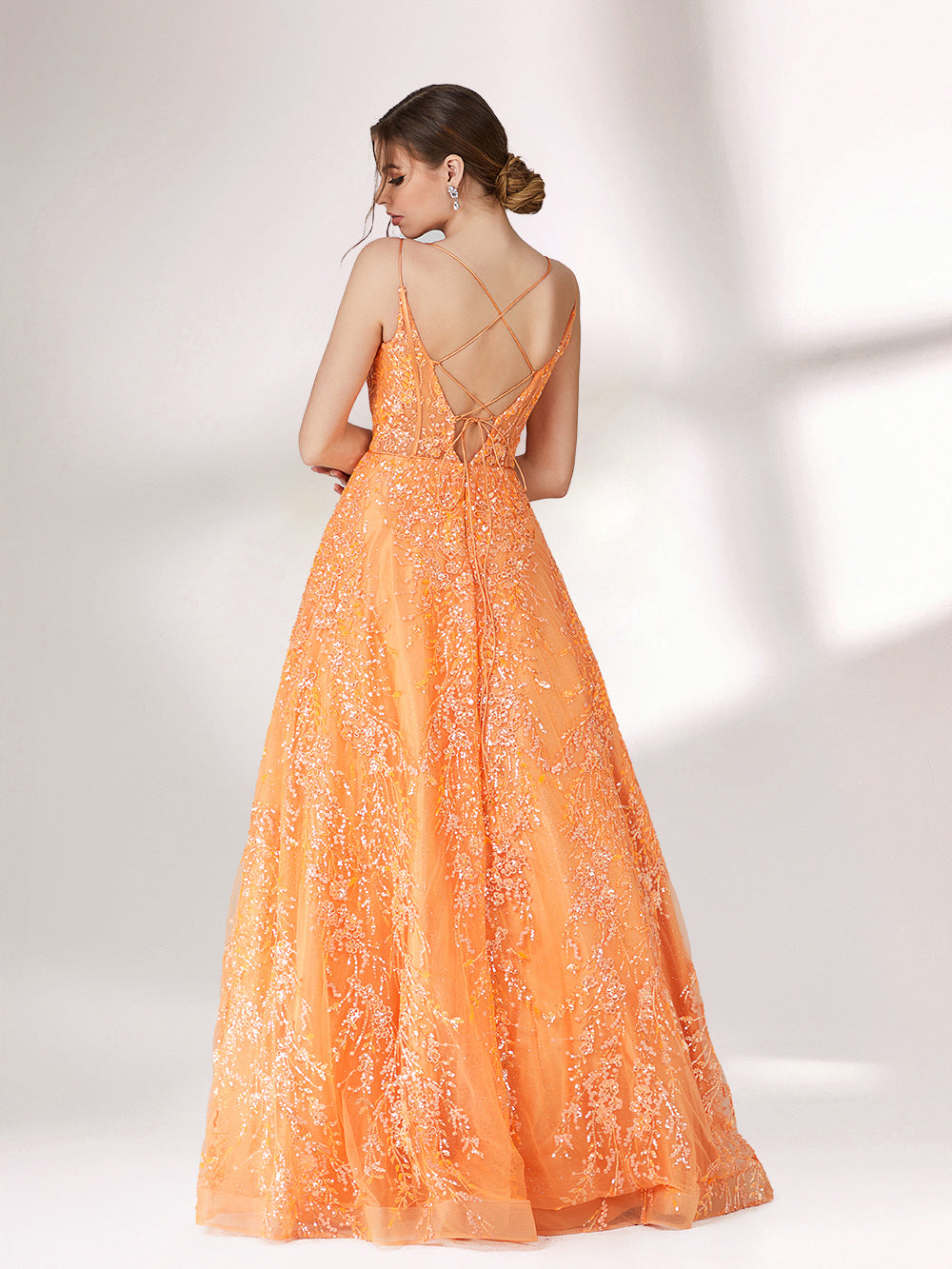 A woman stands against a light background, wearing an orange evening gown. It has thin spaghetti straps, a deep V - neckline, and is adorned with delicate floral - like sequin embroidery all over. The voluminous tulle skirt creates an elegant and glamorous look, perfect for formal events.2