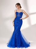 A woman stands against a light background, wearing a bright blue mermaid - style evening gown. It features thin spaghetti straps, a sheer panel at the neckline, and is covered in sparkling sequins. The tulle skirt flares out elegantly, creating a glamorous look perfect for formal events.1