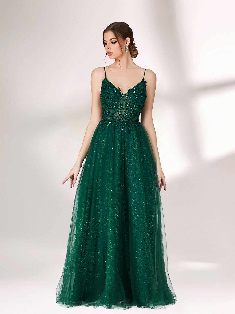 Bathed in soft light, a woman radiates elegance in a dark green evening gown. With sequin - dotted tulle, lace bodice, and spaghetti straps, it crafts a dreamy and refined look for formal events.1