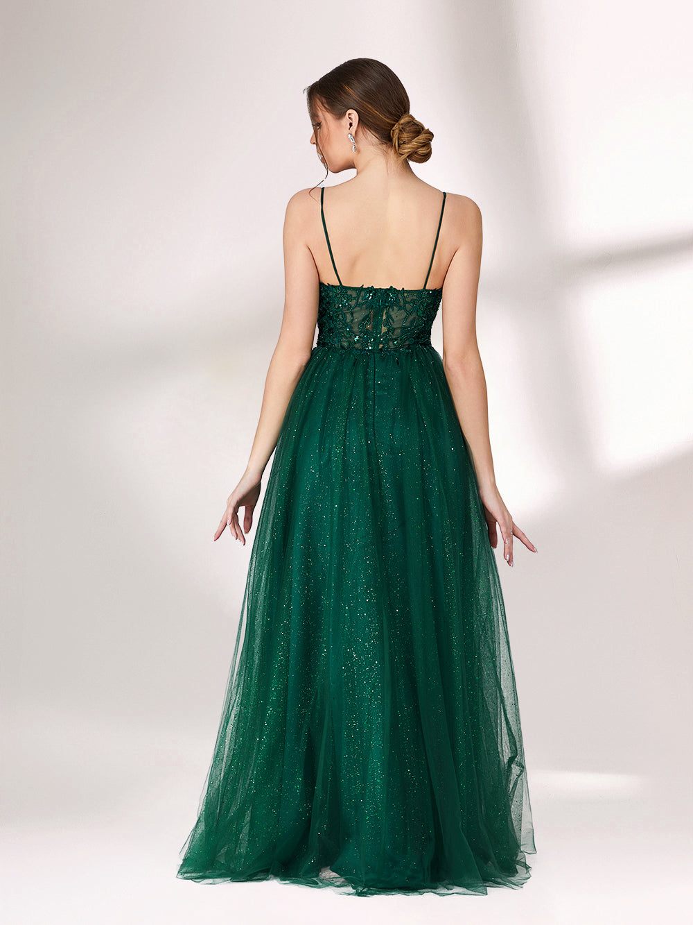 Bathed in soft light, a woman radiates elegance in a dark green evening gown. With sequin - dotted tulle, lace bodice, and spaghetti straps, it crafts a dreamy and refined look for formal events.3