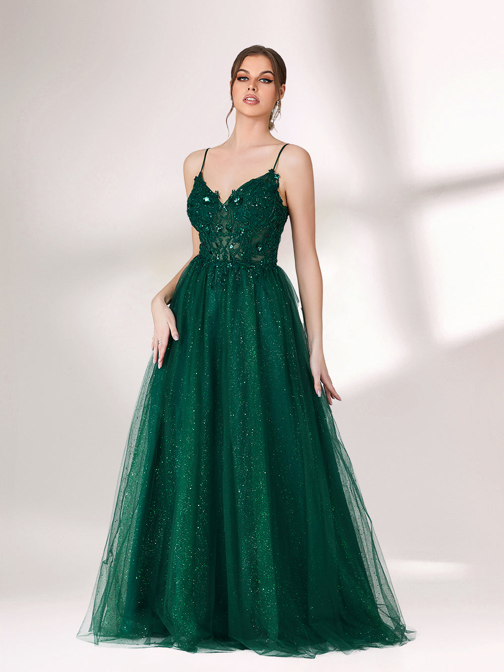 Bathed in soft light, a woman radiates elegance in a dark green evening gown. With sequin - dotted tulle, lace bodice, and spaghetti straps, it crafts a dreamy and refined look for formal events.5