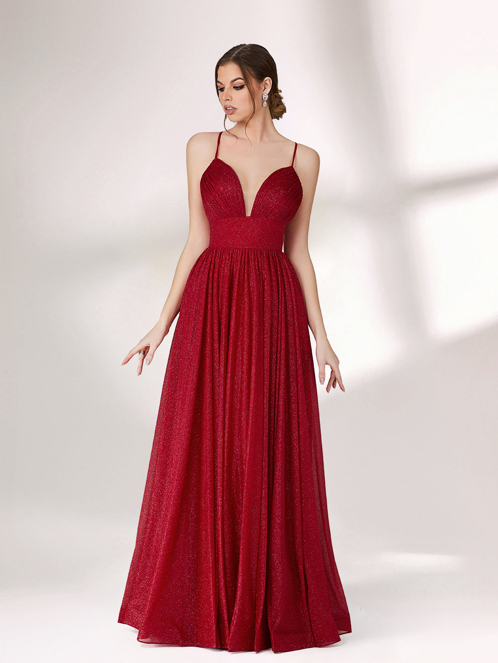 A woman stands against a light background, wearing a deep red evening gown. It has thin spaghetti straps, a deep V - neckline, and a voluminous skirt with a shimmering texture, creating an elegant and glamorous look, perfect for formal events.3