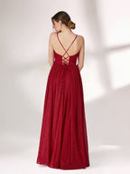 A woman stands against a light background, wearing a deep red evening gown. It has thin spaghetti straps, a deep V - neckline, and a voluminous skirt with a shimmering texture, creating an elegant and glamorous look, perfect for formal events.4