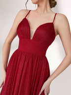 A woman stands against a light background, wearing a deep red evening gown. It has thin spaghetti straps, a deep V - neckline, and a voluminous skirt with a shimmering texture, creating an elegant and glamorous look, perfect for formal events.6