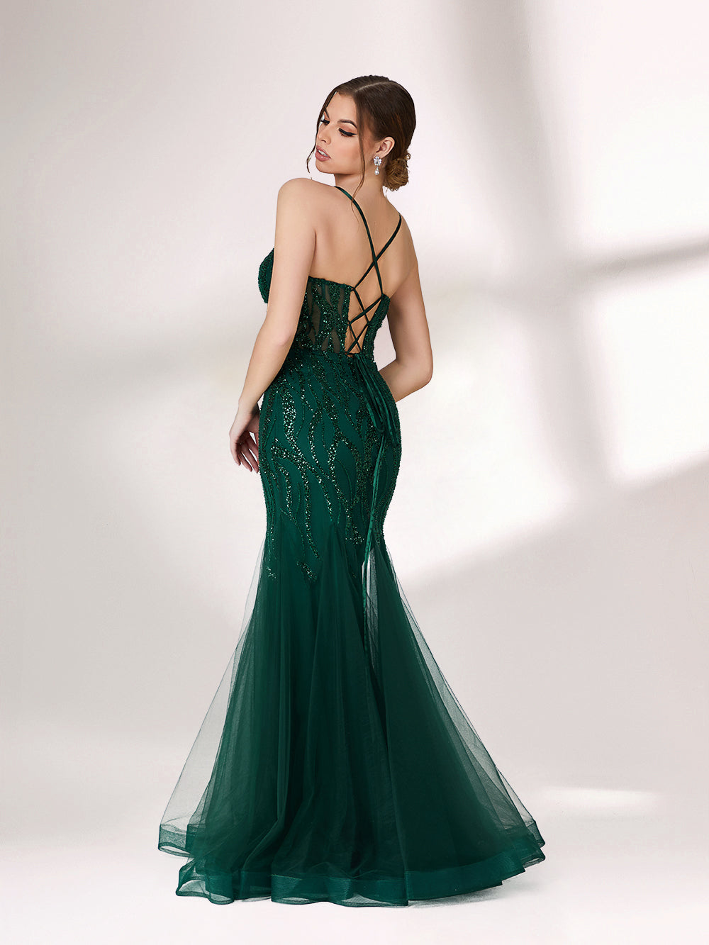 ：Illuminated softly, a woman captivates in a dark green evening gown. With sequin - tulle, mermaid silhouette, and sheer details, it creates a glamorous and sophisticated look for formal events.2