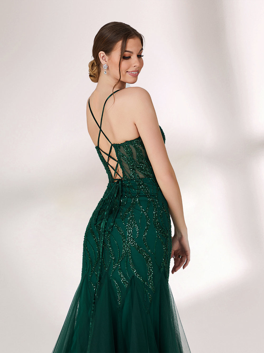 Illuminated softly, a woman captivates in a dark green evening gown. With sequin - tulle, mermaid silhouette, and sheer details, it creates a glamorous and sophisticated look for formal events.6