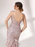 Illuminated softly, a woman captivates in a pink - purple evening gown. With sequin and feather details, a mermaid silhouette, and a high slit, it creates a glamorous and alluring look for formal events.6
