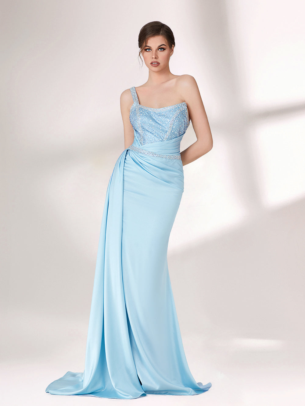 A woman stands against a light background, wearing a light blue evening gown. It has a one - shoulder design, with the bodice adorned with delicate beadwork. A bejeweled waistband cinches the waist, and the skirt, made of smooth satin, flows down to the floor with a small train, creating an elegant and graceful look, perfect for formal events.3