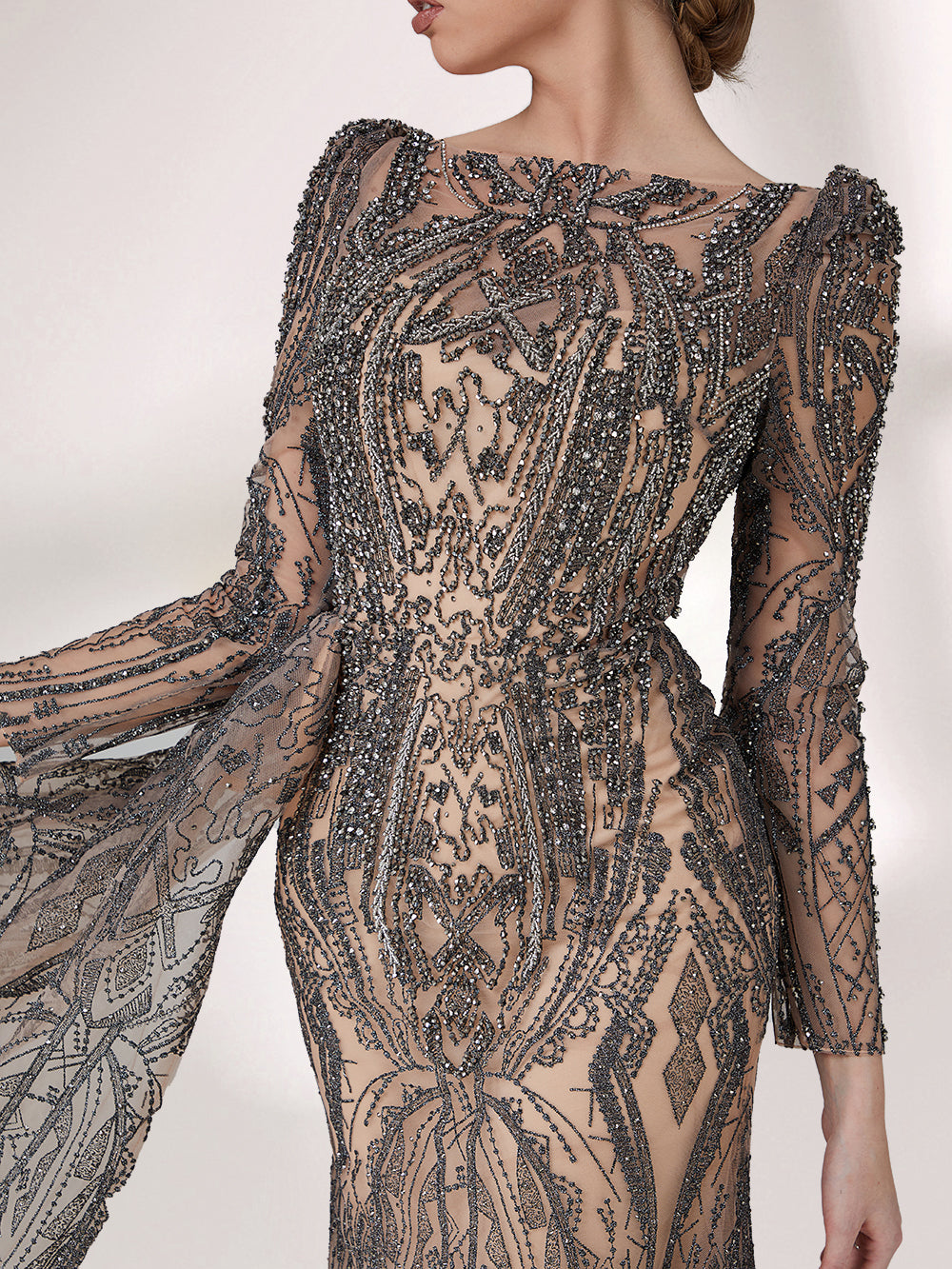 Under subtle lighting, a woman exudes elegance in a long - sleeved evening gown. The gown features a bateau neckline, intricate beadwork and lace patterns, creating a sheer - effect that's both sophisticated and alluring. Ideal for high - end formal occasions, it seamlessly combines luxury and grace.2