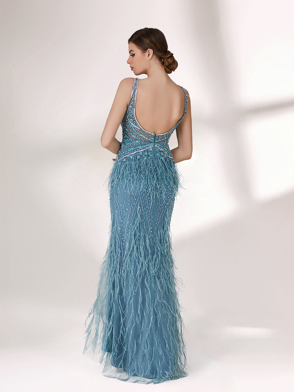 In soft lighting, a woman dazzles in a blue evening gown. With feather details, sequin embellishments, and a mermaid silhouette, it creates a luxurious and eye - catching look for formal events.2