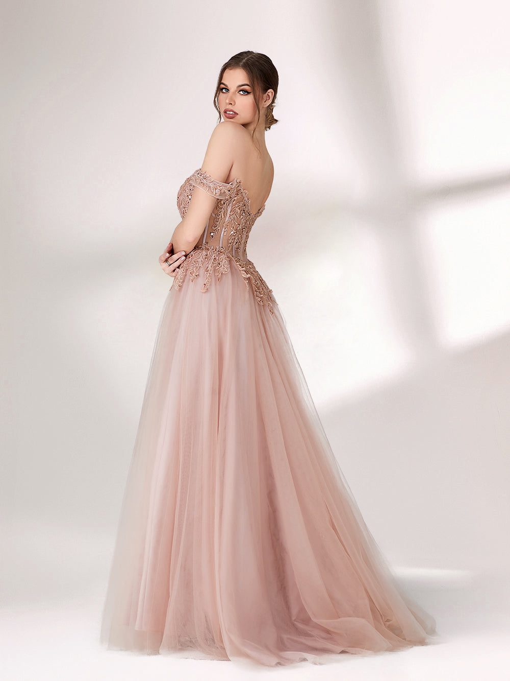 A woman stands against a light background, wearing a blush - pink evening gown. It has an off - the - shoulder design with a sweetheart neckline. The bodice is adorned with intricate lace and bead embroidery, and the skirt is made of flowing tulle, creating an elegant and romantic look, perfect for formal events.2