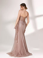 A woman stands against a light background, wearing a blush - toned strapless evening gown. The bodice features intricate floral embroidery, and there's a draped, embroidered tulle overlay on the skirt with a small train. The design is elegant and romantic, suitable for formal events.2