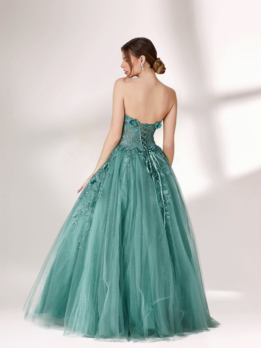 Bathed in soft light, a woman radiates grace in a mint - green evening gown. With floral details, sheer waist, and tulle skirt, it crafts a romantic and elegant look for formal events.2