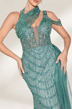 A woman with an elegant updo and a poised stance wears a teal, beaded gown. It has a high - neck, cut - out shoulder design, a form - fitting bodice, and a high side slit. A flowing tulle train adds drama. Paired with silver heels, it's perfect for formal events like galas, radiating glamour.5