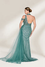 A woman with an elegant updo and a poised stance wears a teal, beaded gown. It has a high - neck, cut - out shoulder design, a form - fitting bodice, and a high side slit. A flowing tulle train adds drama. Paired with silver heels, it's perfect for formal events like galas, radiating glamour.2