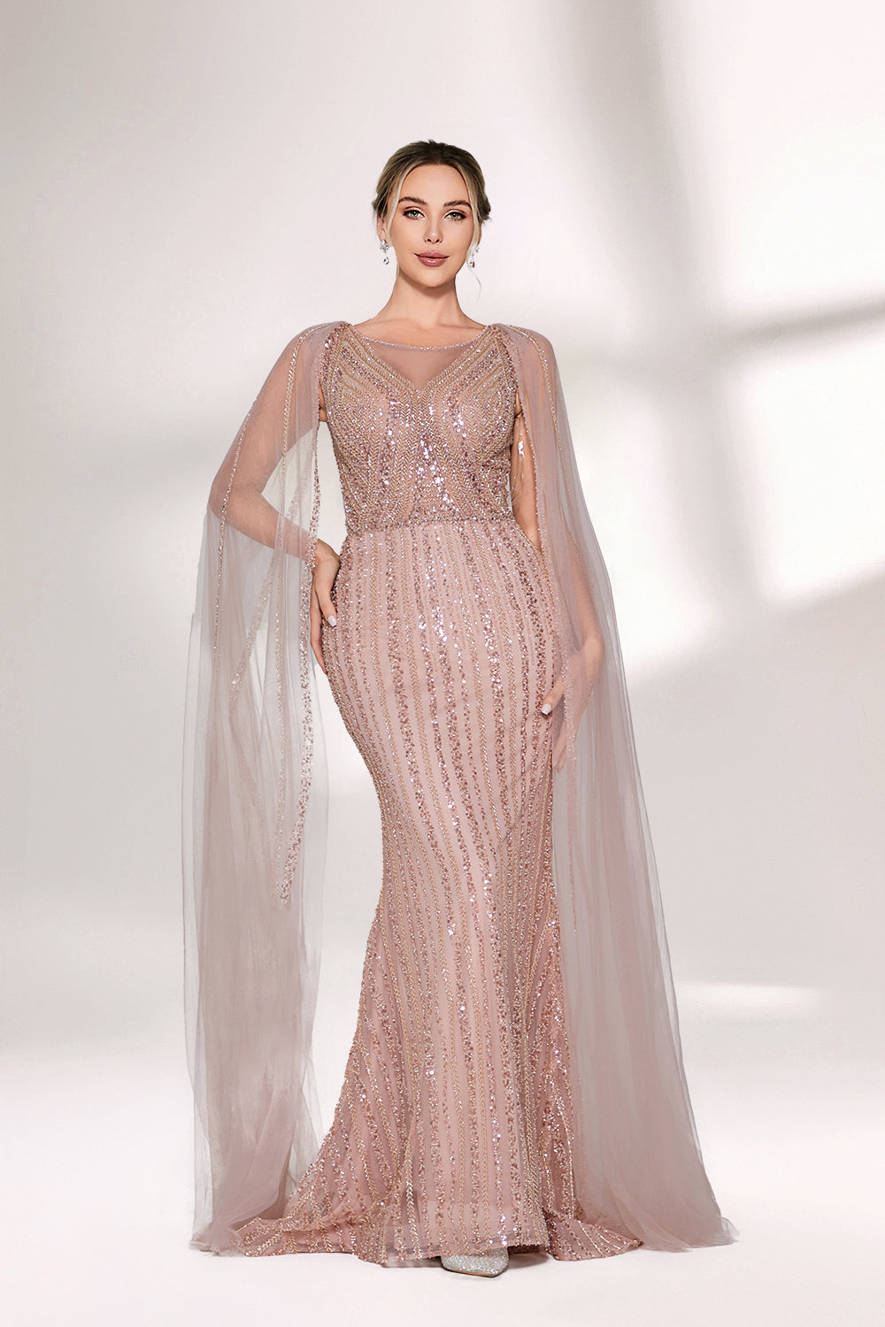 Bathed in gentle light, a woman radiates glamour in a nude - pink sequined mermaid gown. The sheer cape - like sleeves add an ethereal touch, while the body - hugging silhouette and shimmering sequins create a show - stopping, elegant look for formal events.1