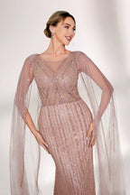 Bathed in gentle light, a woman radiates glamour in a nude - pink sequined mermaid gown. The sheer cape - like sleeves add an ethereal touch, while the body - hugging silhouette and shimmering sequins create a show - stopping, elegant look for formal events.2