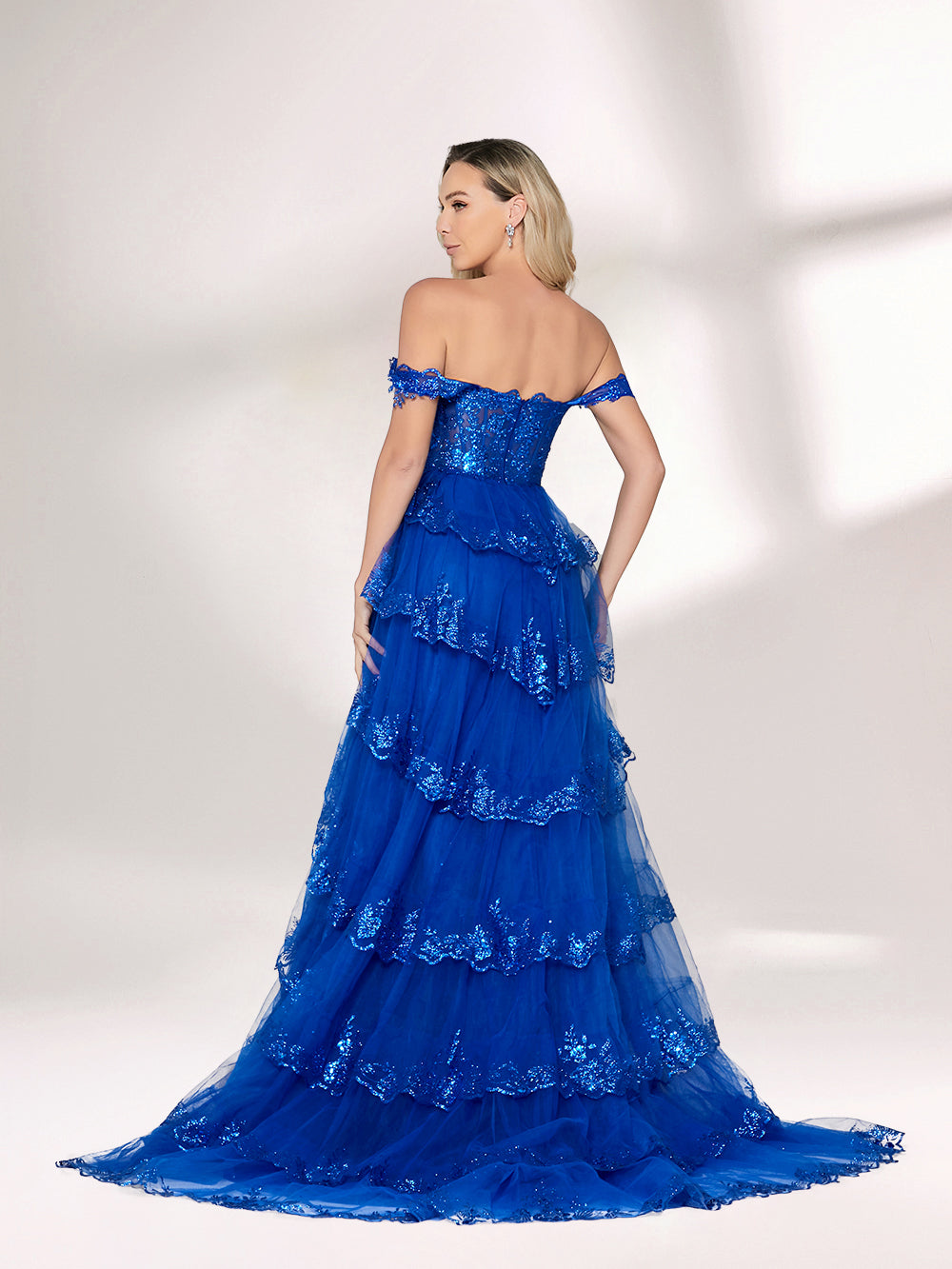 A woman stands against a light background, wearing a royal - blue tulle gown with sequin embellishments. It has an off - shoulder design, a sweetheart neckline, and a tiered skirt. The sparkling sequins and flowing fabric exude romance, perfect for formal events like weddings or galas.2