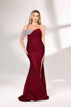 A woman with long, wavy blonde hair and a poised stance wears a deep - red satin mermaid gown. It has an asymmetrical neckline with one shoulder adorned by sparkling, dangling embellishments and a high side slit. Paired with simple heels, the outfit radiates elegance, perfect for formal events like galas.01