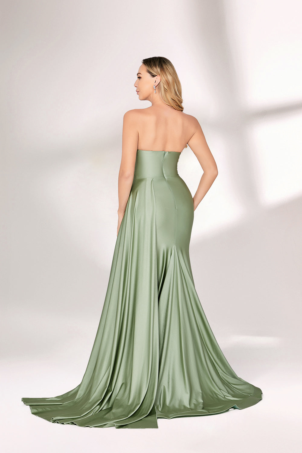 A woman with long blonde hair and poised stance wears a vibrant purple satin gown. It has thin straps, a cowl neckline, and a figure-hugging fit that contours curves. The mermaid skirt falls to the floor with a subtle train. Purple satin shines, exuding luxury. Her natural makeup and understated elegance complement it. Paired with simple accessories, it’s ideal for galas, blending grace and glamour.03
