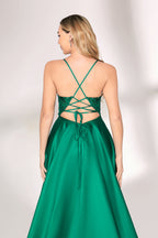 A woman with long, wavy blonde hair and a confident pose wears a rich green satin gown. It features thin spaghetti straps, a beaded and sequined bodice, and a high side slit. Paired with silver heels, the outfit radiates elegance, ideal for formal events like galas or evening receptions.03