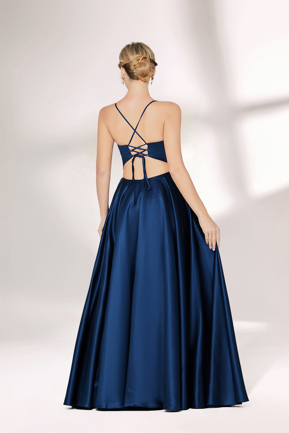 A woman with short, sleek hair and a poised demeanor wears a navy - blue satin gown. It has thin spaghetti straps, a sweetheart neckline, and a voluminous, flowing skirt. Paired with understated heels, the outfit radiates elegance, ideal for formal events like galas or weddings.02