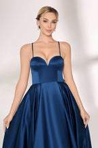 A woman with short, sleek hair and a poised demeanor wears a navy - blue satin gown. It has thin spaghetti straps, a sweetheart neckline, and a voluminous, flowing skirt. Paired with understated heels, the outfit radiates elegance, ideal for formal events like galas or weddings.05