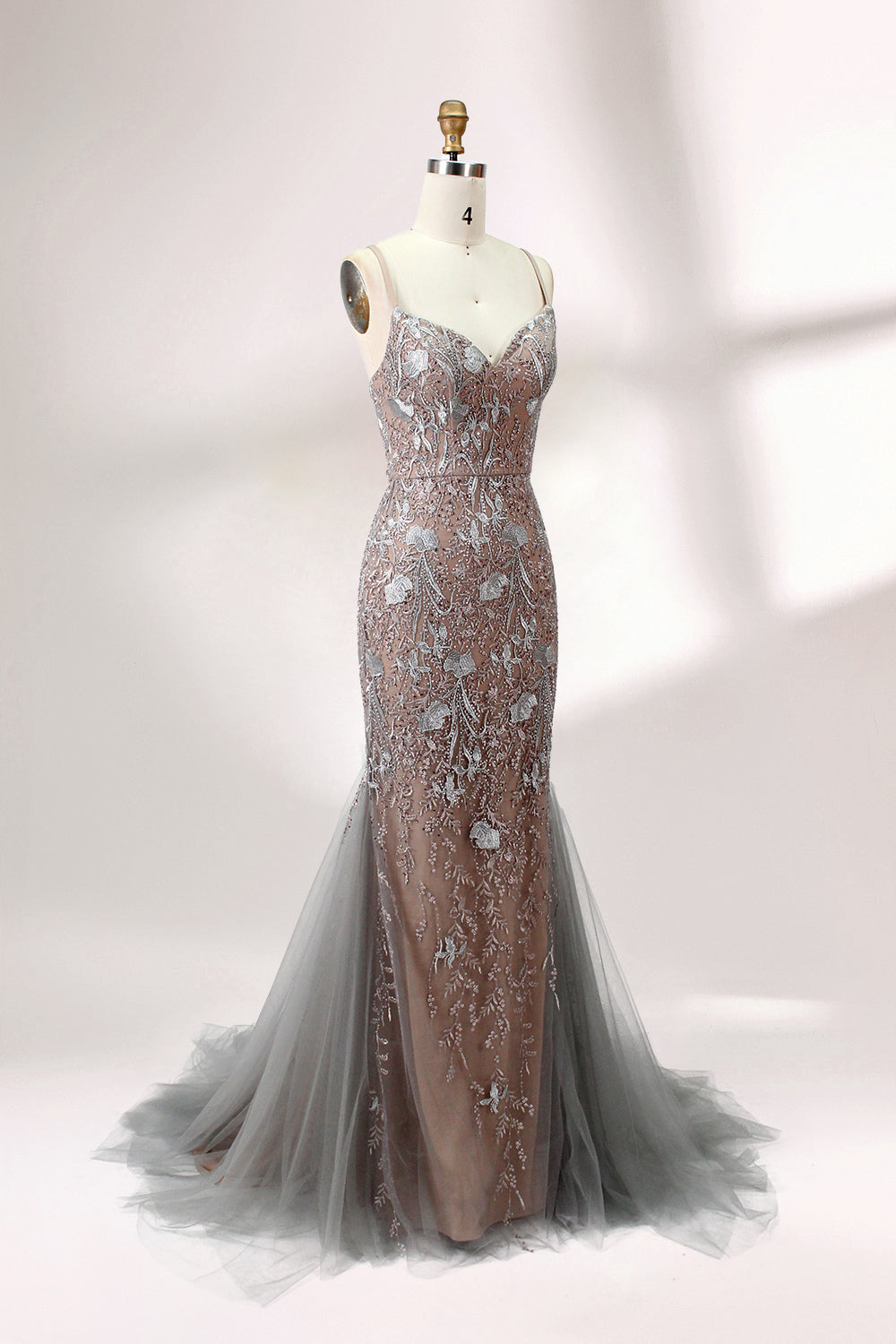 Showcased on a mannequin is a taupe - toned mermaid - cut gown. It has thin straps, a sweetheart neckline, and is embellished with delicate silver floral embroidery all over, plus a flowing tulle skirt. The refined design gives off a glamorous aura, ideal for formal events such as proms or weddings.3
