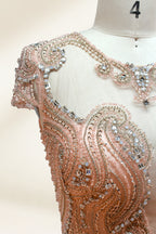 Photograph of an elegant, floor-length, peach-colored evening gown on a mannequin. The gown features intricate, sparkling beadwork on the bodice and cap sleeves, and a flowing, sheer skirt. The mannequin has a light beige background, with soft shadows highlighting the gown's details. The dress exudes luxury and sophistication.3132.4