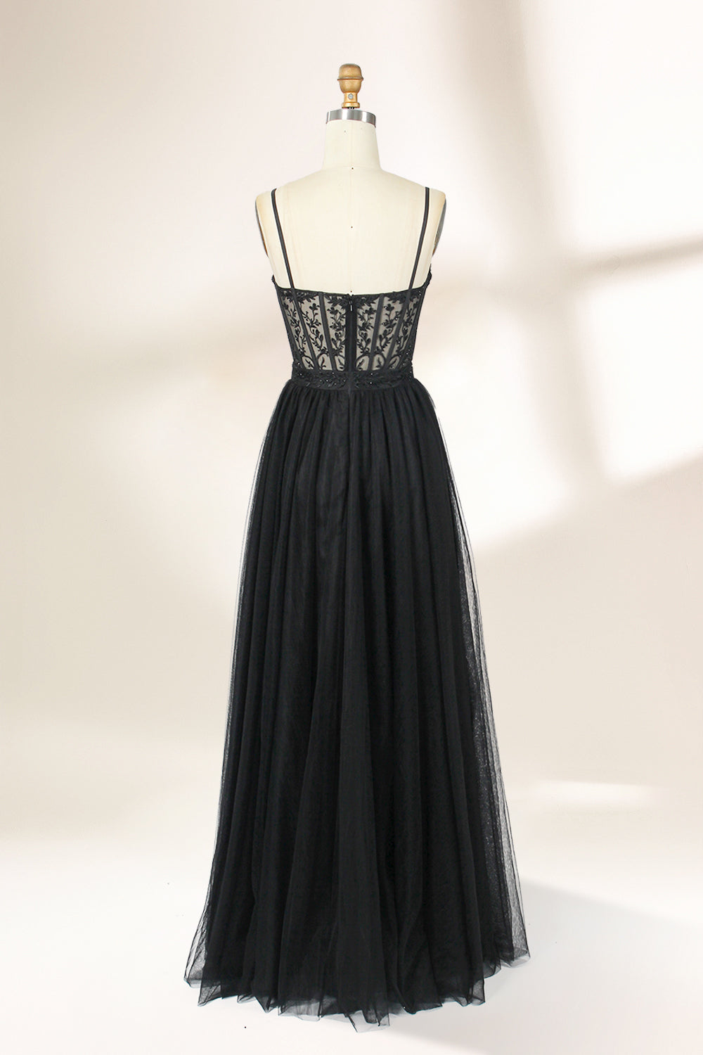 Photograph of a black, lace-trimmed, strapless gown with a sweetheart neckline and a full, flowing tulle skirt. The dress is displayed on a white mannequin with a wooden stand against a plain, light beige background, creating a simple and elegant setting.32547c-2.2