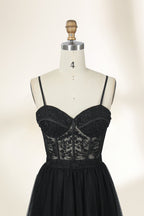 Photograph of a black, lace-trimmed, strapless gown with a sweetheart neckline and a full, flowing tulle skirt. The dress is displayed on a white mannequin with a wooden stand against a plain, light beige background, creating a simple and elegant setting.32547c-2.3