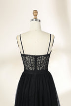 Photograph of a black, lace-trimmed, strapless gown with a sweetheart neckline and a full, flowing tulle skirt. The dress is displayed on a white mannequin with a wooden stand against a plain, light beige background, creating a simple and elegant setting.32547c-2.4