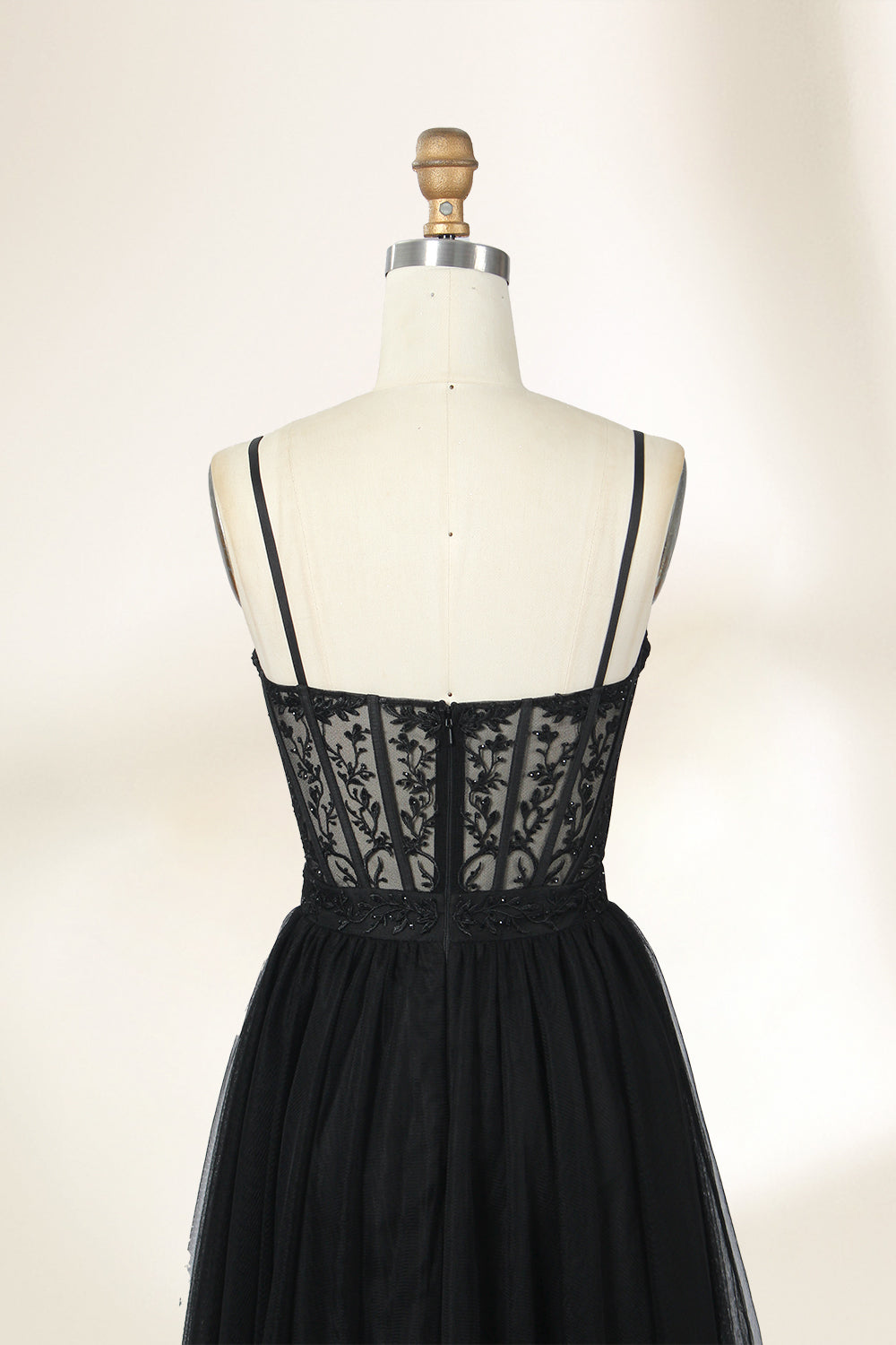 Photograph of a black, lace-trimmed, strapless gown with a sweetheart neckline and a full, flowing tulle skirt. The dress is displayed on a white mannequin with a wooden stand against a plain, light beige background, creating a simple and elegant setting.32547c-2.4