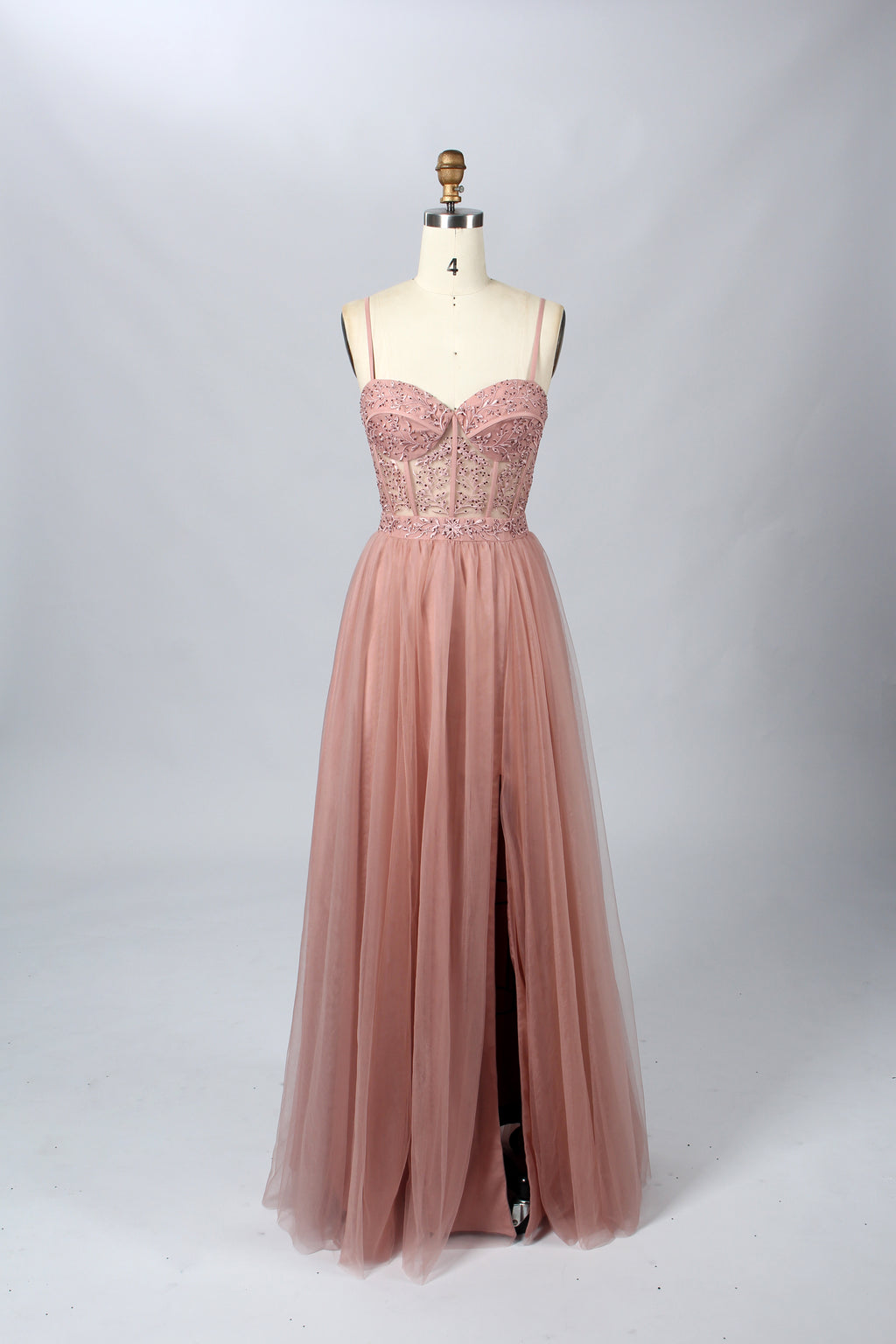 Photograph of a black, lace-trimmed, strapless gown with a sweetheart neckline and a full, flowing tulle skirt. The dress is displayed on a white mannequin with a wooden stand against a plain, light beige background, creating a simple and elegant setting.32547c-2.7