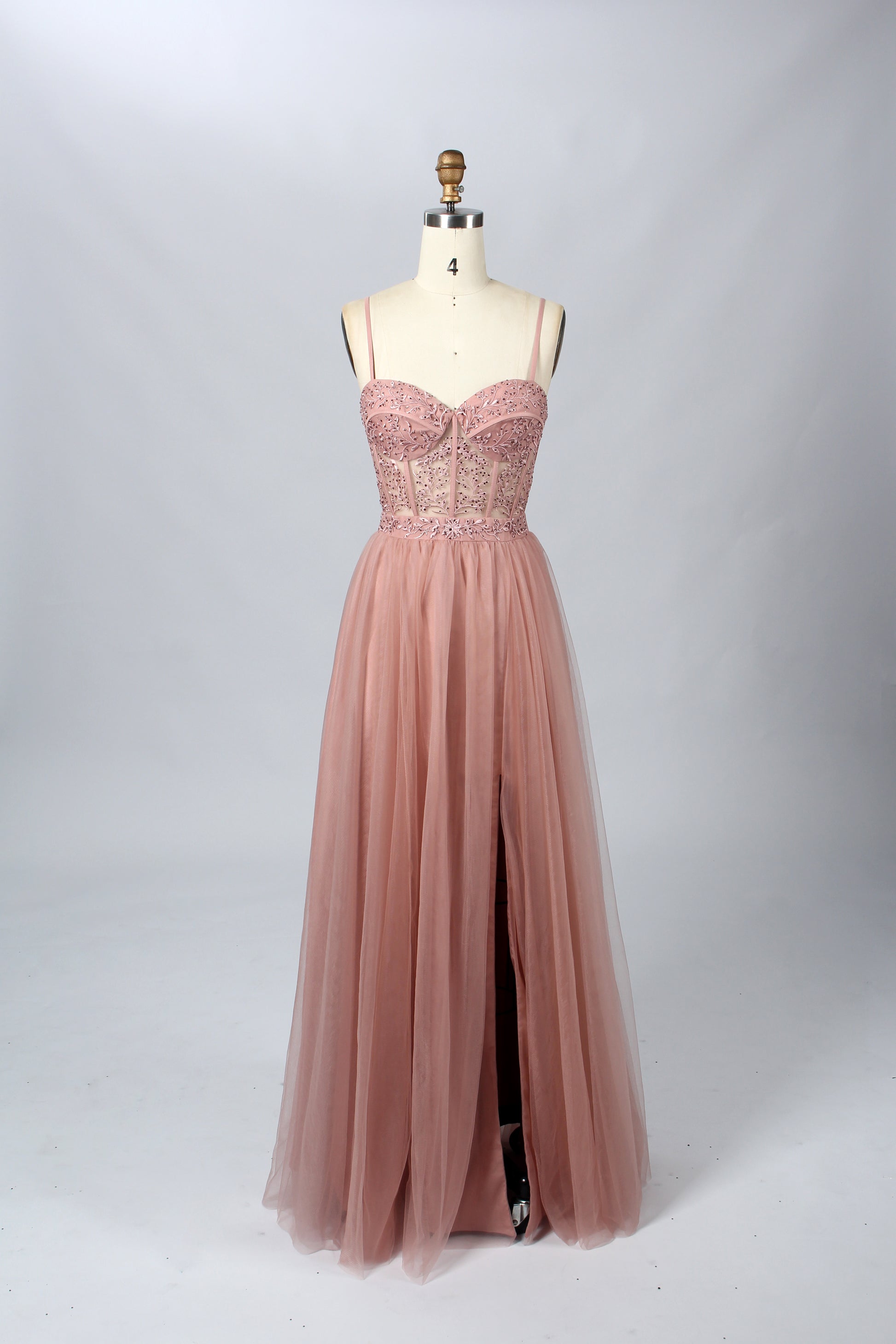 Photograph of a black, lace-trimmed, strapless gown with a sweetheart neckline and a full, flowing tulle skirt. The dress is displayed on a white mannequin with a wooden stand against a plain, light beige background, creating a simple and elegant setting.32547c-2.7